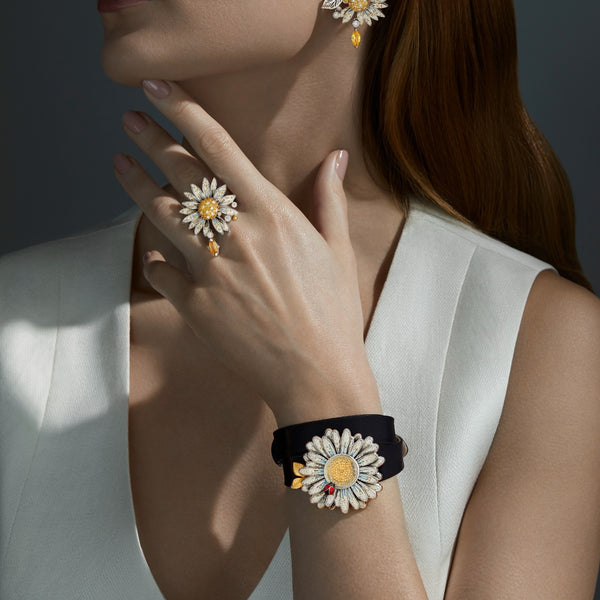 Woman wearing flower-themed earrings and bracelet against a dark background