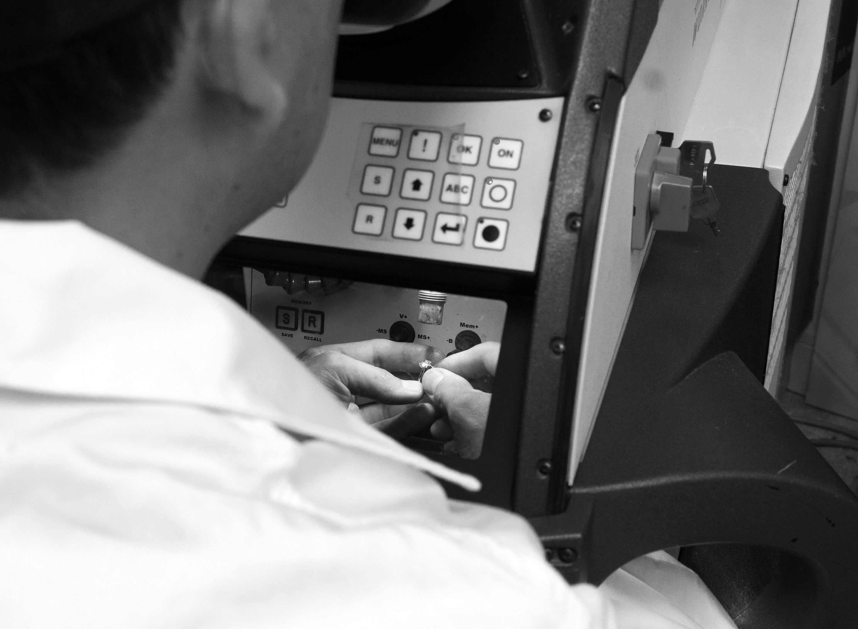 Black and white image of man using tools to custom design jewelry