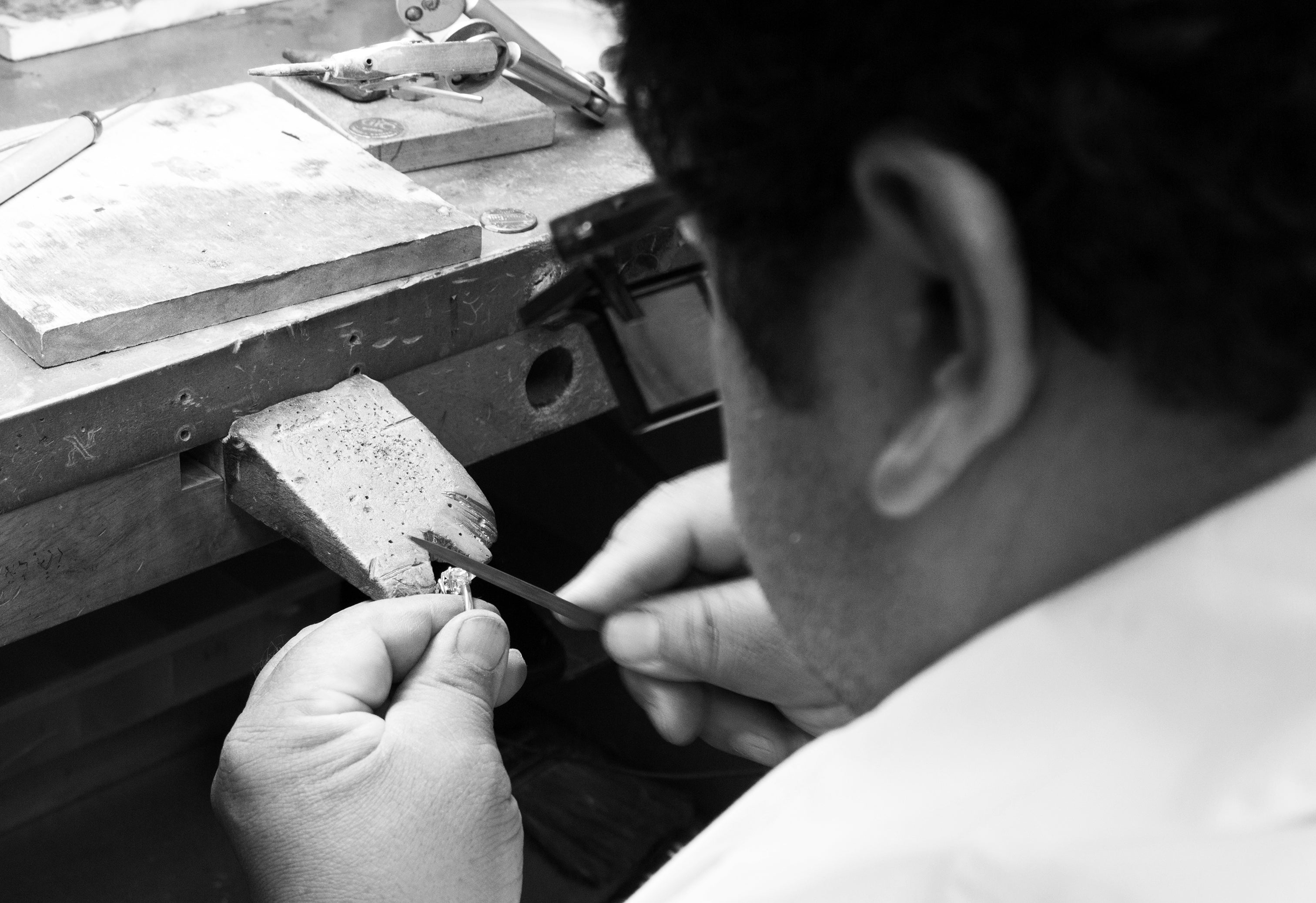 Black and white image of man using tools to custom design jewelry