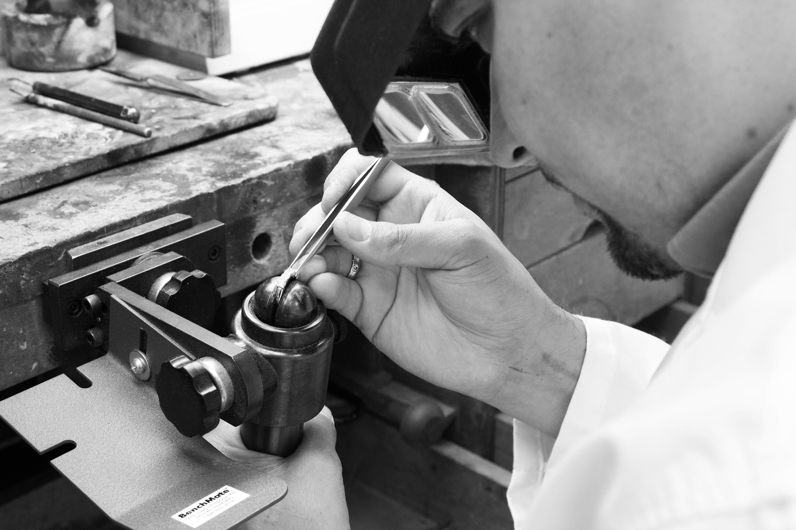 Black and white image of man using tools to custom design jewelry