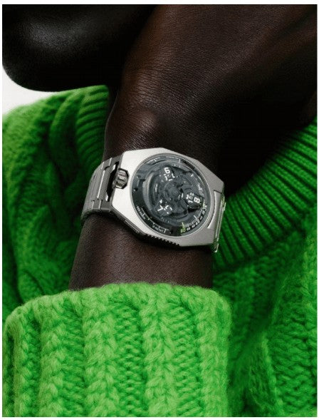 Close Up Lifestyle Image of URWERK UR - 100V Magic T “Hunter Green”. Picture of a man in lime green sweater displaying watch on his wrist.