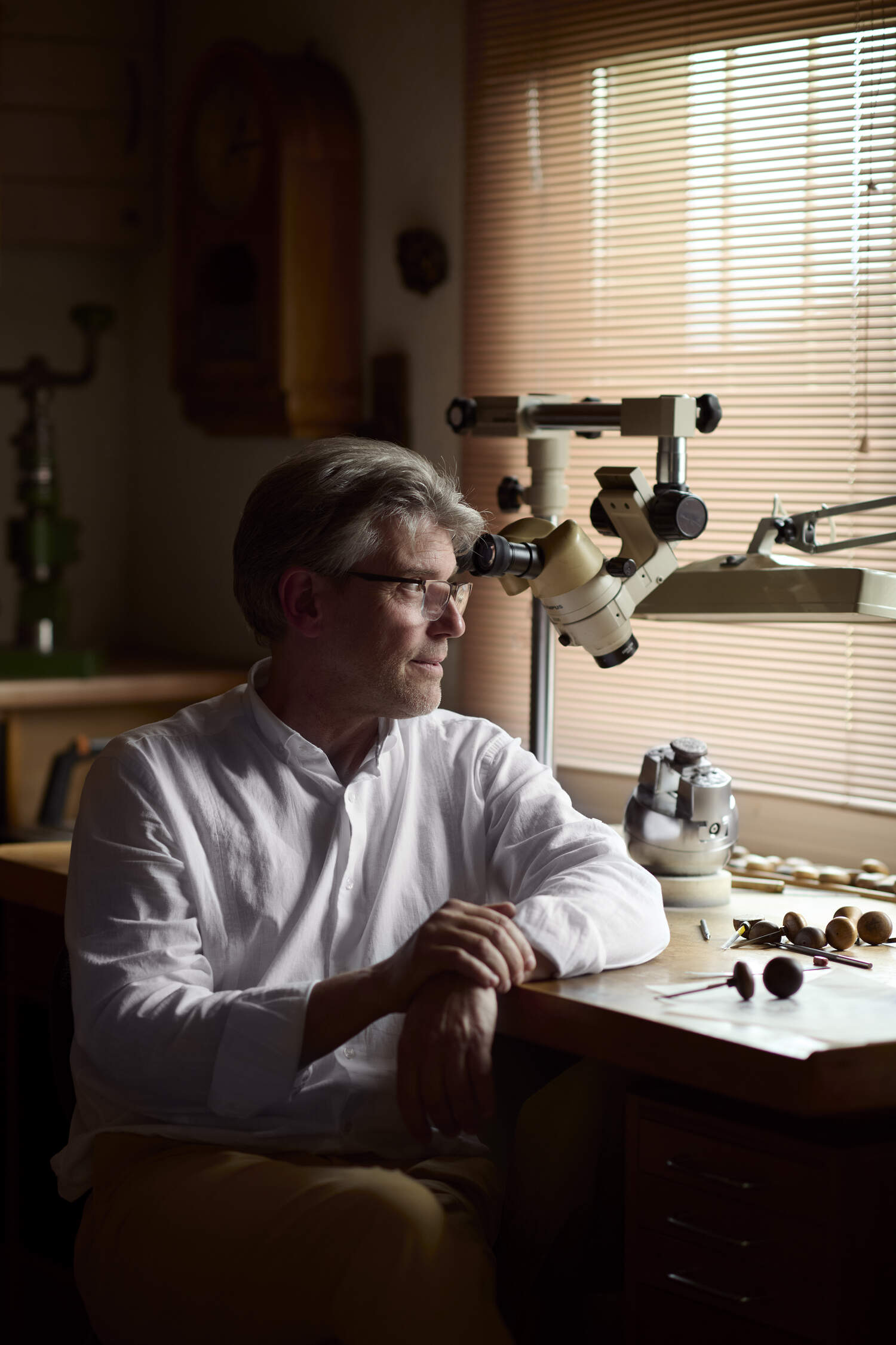 Master Engraver, Eddy Jacquet sitting at his work station in a white shirt.